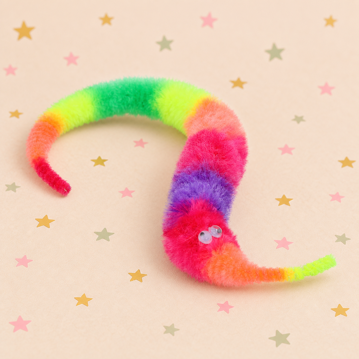 Pickit Parties rainbow fuzzy fluffy twisty worm toy with googly eyes on a star-patterned background